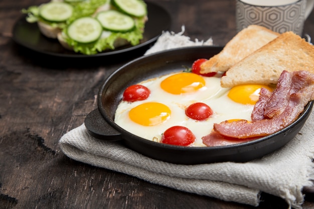 Frühstück mit eiern, kirschtomaten, speck und frisch geröstetem toast Premium Fotos