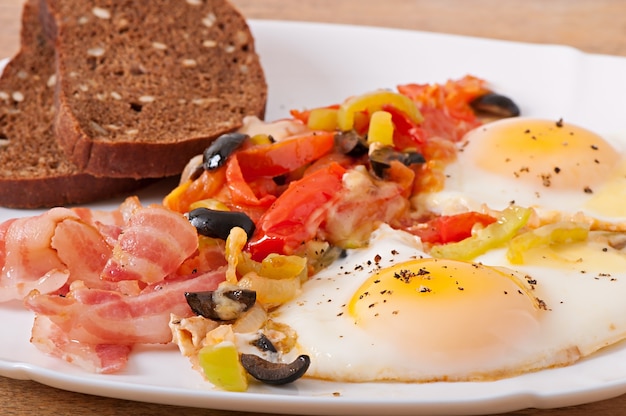 Frühstück - spiegeleier mit speck, tomaten, oliven und käsescheiben ...