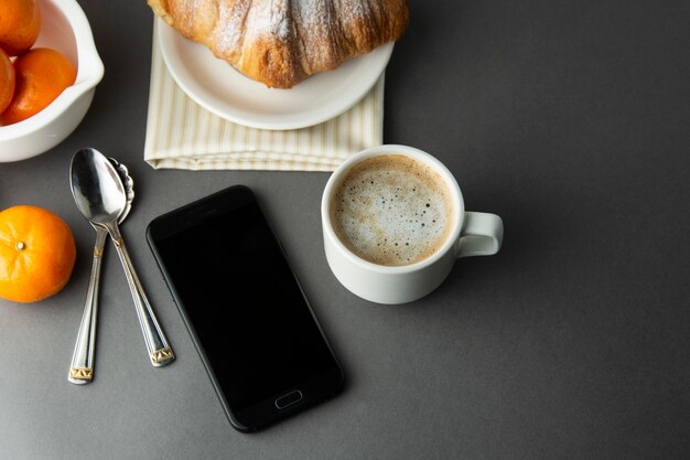 Frühstückskaffee mit croissant, französischen zitrusfrüchten, gebäck, einer tasse kaffee oder latte. koffein wird angepriesen. Premium Fotos