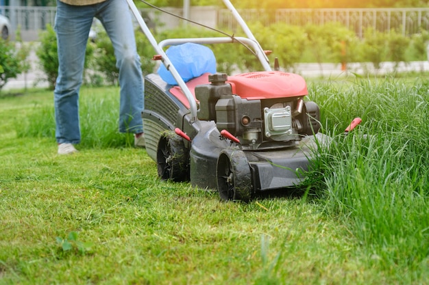 Gärtnerfrauenbeine, die gras mit rasenmäher mähen PremiumFoto