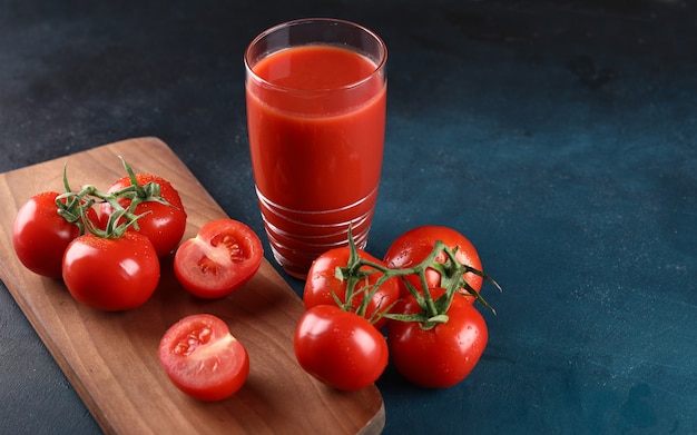 Ganze und geschnittene tomaten und ein glas tomatensaft