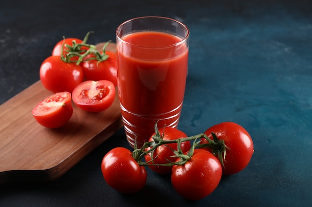 Ganze und geschnittene tomaten und ein glas tomatensaft