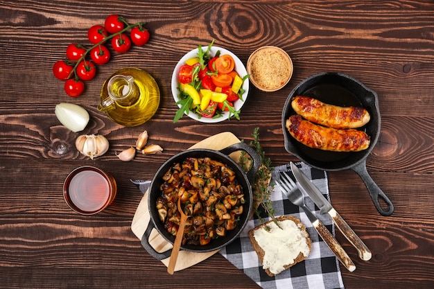 Gebratene champignons und wurst in einer gusseisenpfanne. zutaten für rustikales einfaches essen, ansicht von oben. Premium Fotos