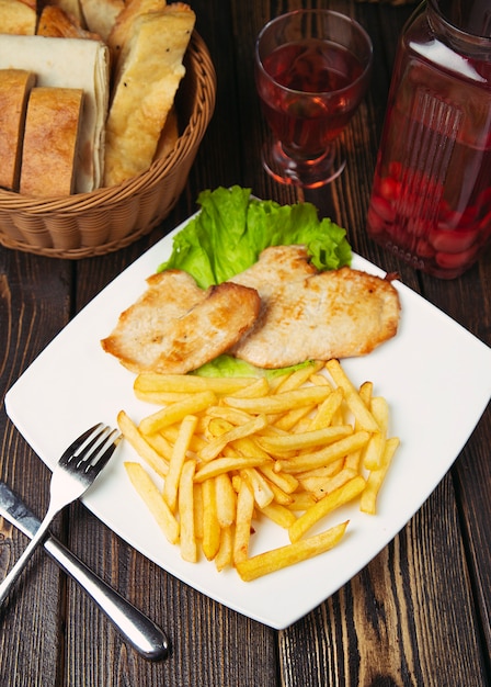 Gebratene hähnchenbrustnuggets mit pommes-frites in der weißen platte ...