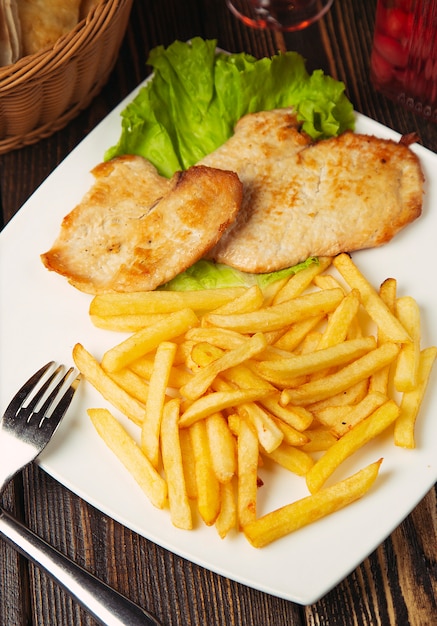 Gebratene hähnchenbrustnuggets mit pommes-frites in der weißen platte ...