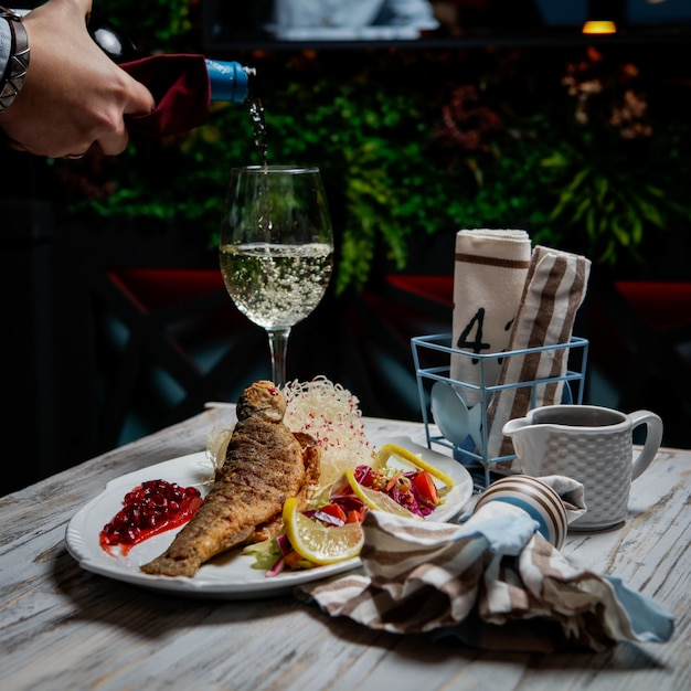 Gebratener fisch der seitenansicht mit glas wein und