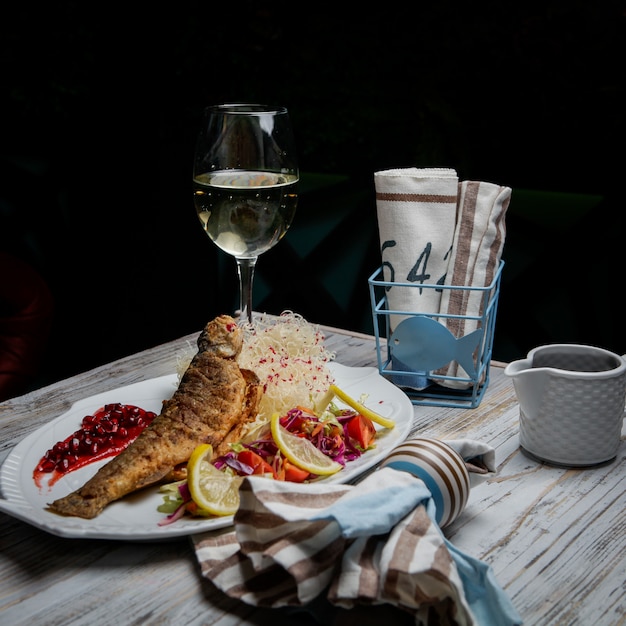 Gebratener fisch von der seitenansicht mit glas wein und