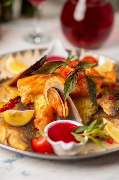 Gebratener gegrillter fisch und meeresfrüchte, serviert mit kräutern, zitrone und diproter tomatensauce. Kostenlose Fotos