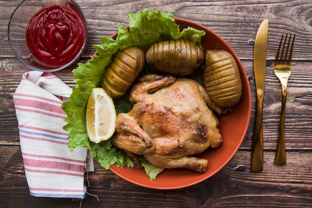 Gebratenes hähnchen in schüssel mit kartoffeln messer; serviette ...