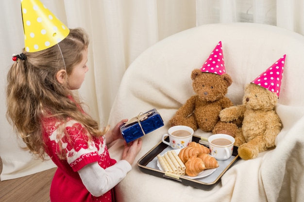 Geburtstagsfeier, mädchenkind im festlichen hut, der mit teddybären spielt  Premium-Foto