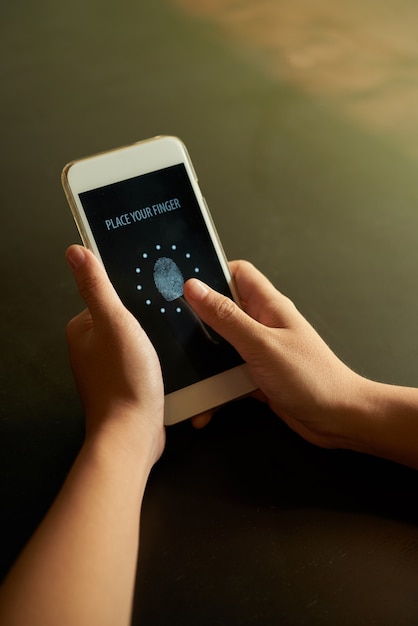 Geerntete hände, die fingerabdruck auf smartphone scannen Kostenlose Fotos