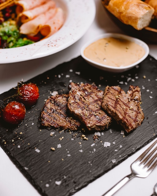 Gegrilltes fleisch mit kräuter-tomaten-salz-brotsauce seitenansicht ...