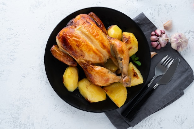 Gegrilltes ganzes huhn in der platte auf weißer tabelle, gebackenes fleisch mit kartoffeln. draufsicht, kopie, raum Premium Fotos
