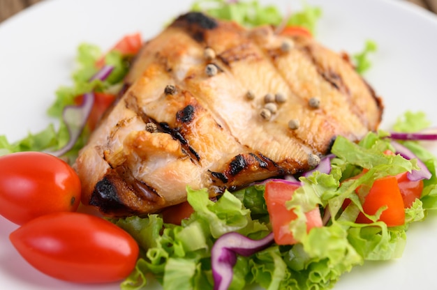 Gegrilltes hähnchen auf einem weißen teller mit einem salat aus tomaten ...