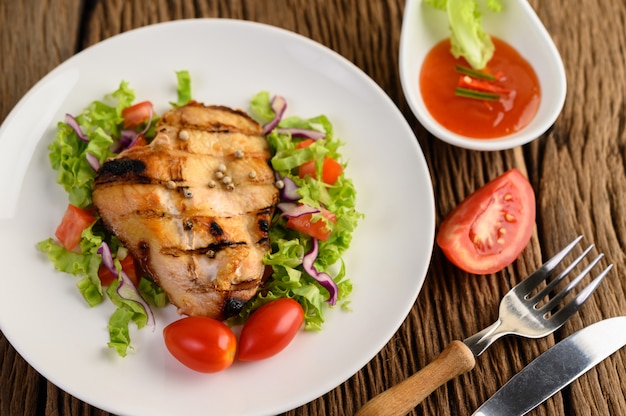 Gegrilltes hähnchen auf einem weißen teller mit einem salat aus tomaten ...