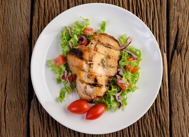 Gegrilltes hähnchen auf einem weißen teller mit salat, tomaten, in ...