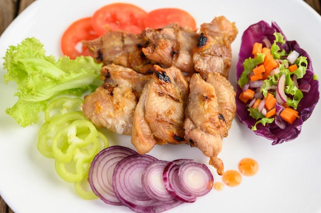 Gegrilltes hähnchen auf einem weißen teller mit salat, tomaten, roten ...