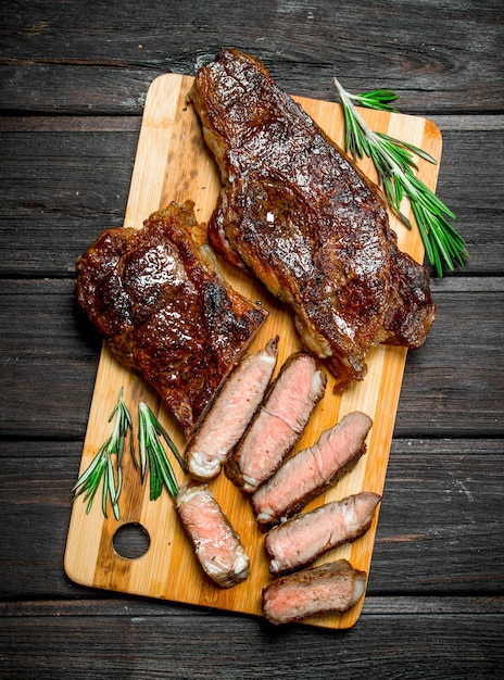 Gegrilltes rindersteak mit kräutern und gewürzen. auf einem holztisch ...