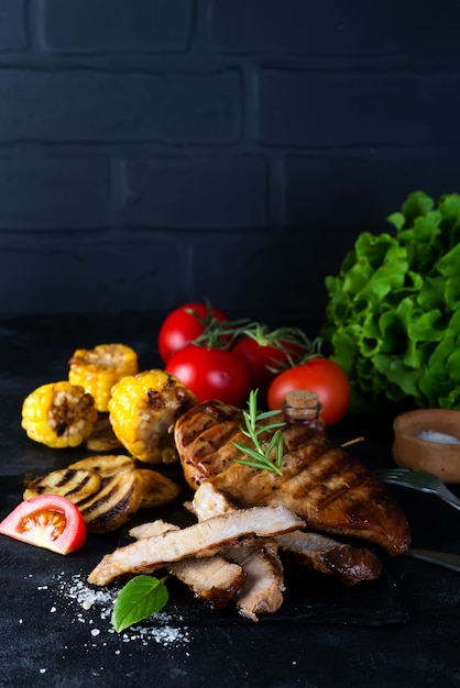 Gegrilltes steak und gemüse, ofenkartoffeln und grüner salat auf dunkelheit Premium Fotos
