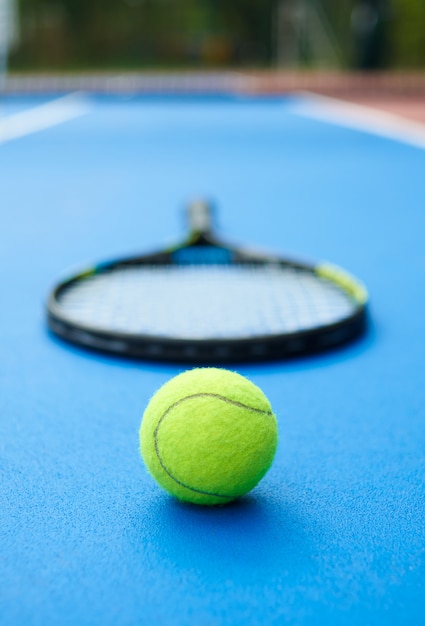 Gelber ball liegt auf blauem tennisplatzteppich mit professionellem