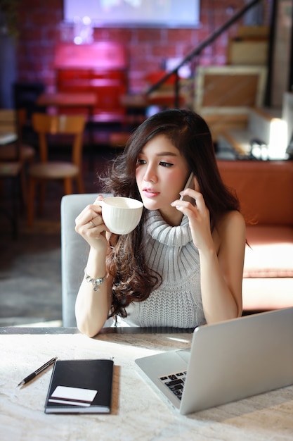 Geschäft in voller länge, das online, junge asiatische frau im freizeitkleid arbeitet an computer verkauft Premium Fotos
