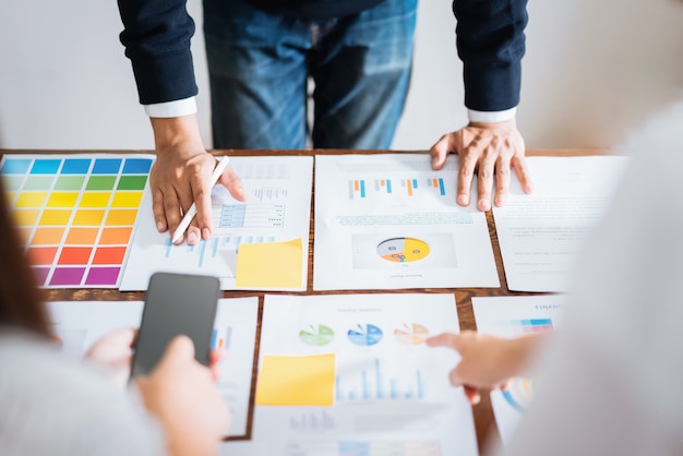 Geschäftsleute, die das team arbeitet an hölzernem schreibtisch- und handmann zeigt auf finanzdokumente im büro treffen. strategie für erfolgreiche besprechungsarbeitsplätze. Premium Fotos
