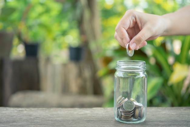 Geschäftsleute legen die münze in ein glas um geld zu