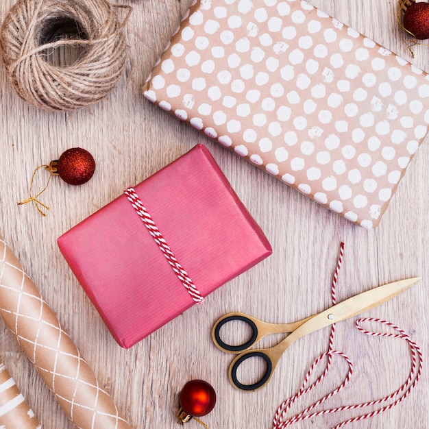 Geschenke verpackt in der nähe von weihnachtskugeln, fäden und scheren Kostenlose Fotos