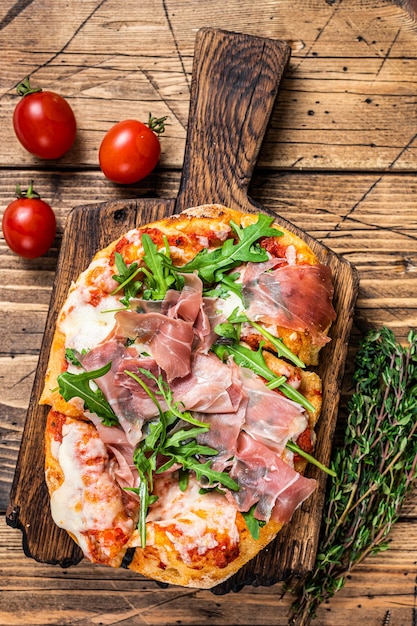 Geschnittene pizza mit schinken-parmaschinken, rucola und parmesan auf ...