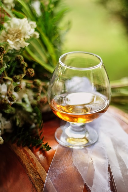 Gläser gefüllt mit weinbrand, ein glas neben der blüte auf dem tisch ...