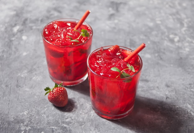 Gläser mit frischem selbst gemachtem erdbeersüßem eistee oder cocktail, limonade mit minze. Premium Fotos