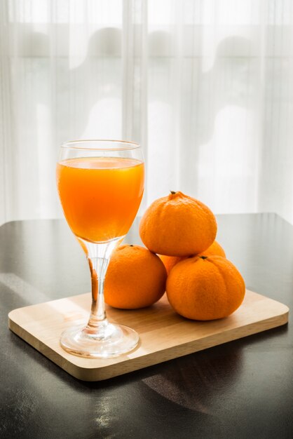 Glas frisch gepresster orangensaft mit vier orangen | Premium-Foto