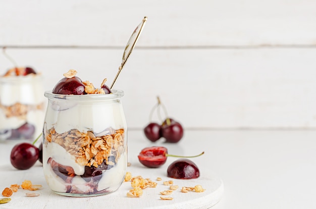 Glas müsli mit griechischem joghurt und süßen kirschen auf