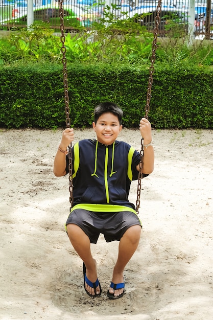 Glückliche asiatische sport junge spielen auf swing