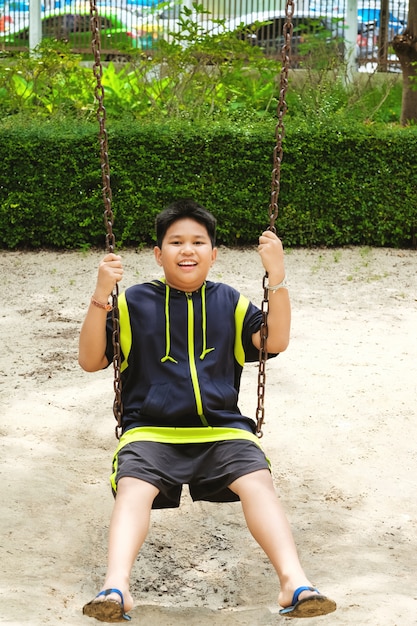 Glückliche asiatische sport junge spielen auf swing