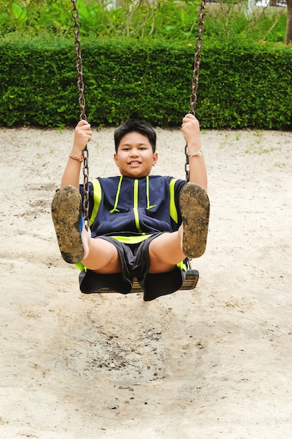 Glückliche asiatische sport junge spielen auf swing
