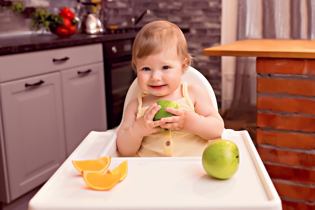 Gluckliches Baby 10 12 Monate Isst Obst Orange Apfel Portrat Eines Glucklichen Madchens In Einem Hochstuhl In Der Kuche Premium Foto