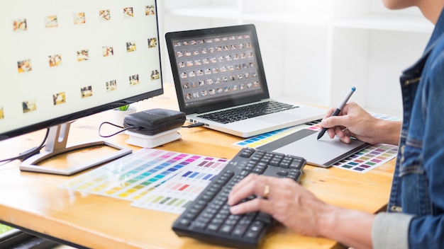 Grafikdesigner-team, das an webdesign unter verwendung der farbmuster, die grafik unter verwendung der tablette und eines stiftes bearbeiten, an den schreibtischen im beschäftigten kreativen büro bearbeitet. Premium Fotos