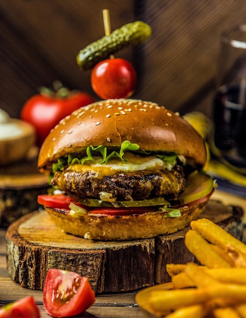 Grosser Maximaler Burger Der Auf Einem Stuck Holz Steht Kostenlose Foto