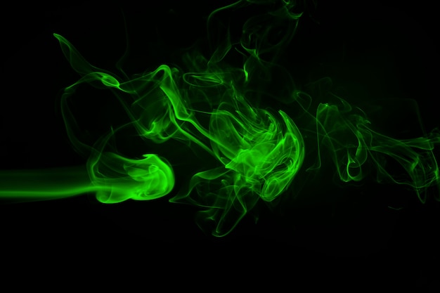 Grüne rauchzusammenfassung auf einem schwarzen hintergrund, dunkelheitskonzept Premium Fotos