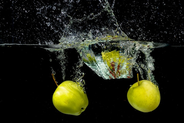 Gruner Apfel Zwei Der Im Wasser Gegen Schwarzen Hintergrund Spritzt Kostenlose Foto