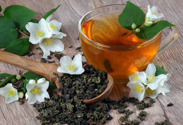 Grüner tee mit jasmin. trockene grüne teeblätter mit jasminblüten in ...