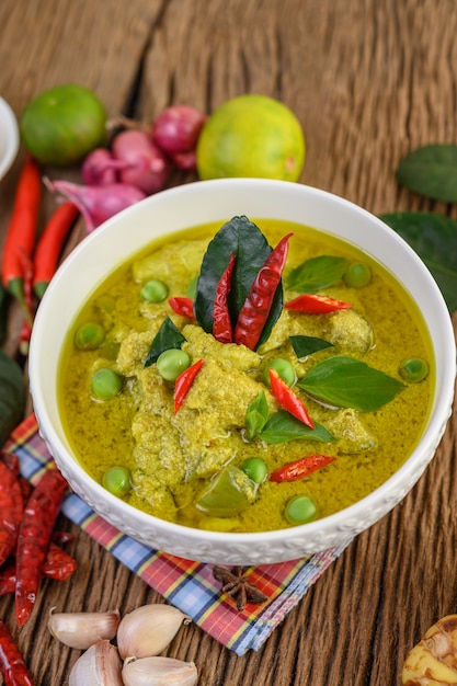 Grünes curry in einer schüssel mit limetten, roten zwiebeln ...