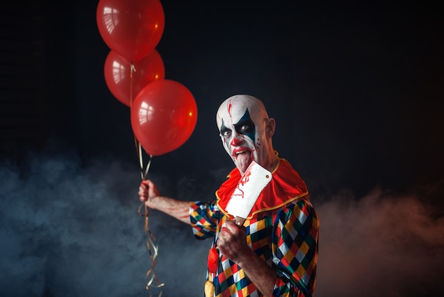 Gruseliger Blutiger Clown Mit Messer Halt Luftballons Entsetzen Mann Mit Make Up Im Karnevalskostum Verruckter Verruckter Premium Foto