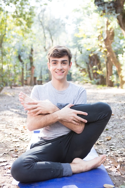 Guy macht yoga-übungen auf der matte im freien ...