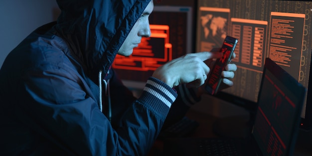 Hacker in der motorhaube zeigt mit dem finger auf das display, das den ort des cyberangriffs im neonlicht anzeigt Premium Fotos