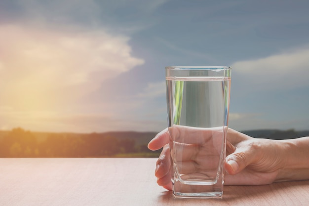 Hand hält ein glas reines wasser. hand, die ein glas