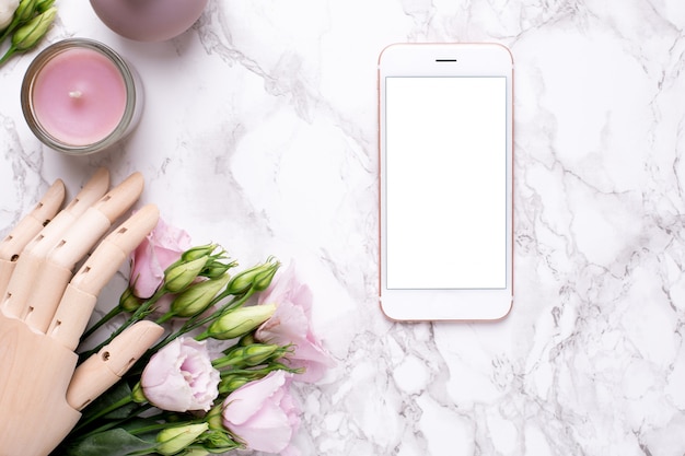 Handy und hölzerne hand mit rosa blumen auf marmor Premium Fotos