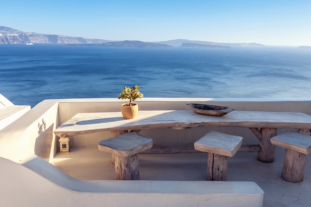 Hausterrasse im freien mit hölzerner weinlesetabelle mit seeansicht in santorini, griechenland. Premium Fotos