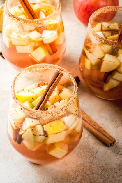 Herbst- und wintergetränke. warme apfelsangria, apfelwein mit fruchtstücken, zimt, gewürzen, zucker. in gläsern auf einem steinbeigen tisch. mit den zutaten. copyspace Premium Fotos